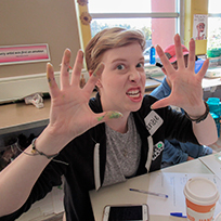 A woman poses for a funny photo with paint-covered hands.