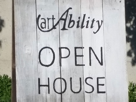 A large wooden sign outside with the artAbility logo on it