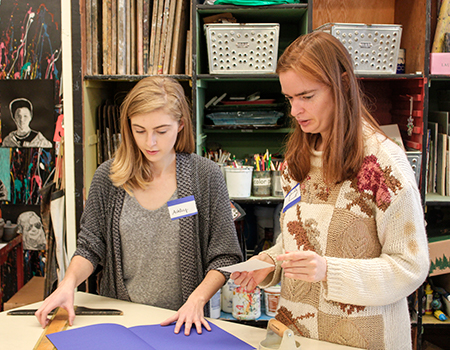 A student volunteer helps a participant set out some colored paper.