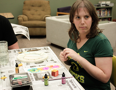 A woman sits at a table with all of her art supplies.