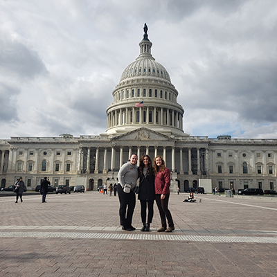 Victoria, Kellie and Maddie are standing together, posing, with the Capitol Building in the background. Click to enlarge.