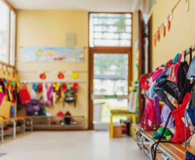 An elementary school hallway with loads of colorful coats and backpacks hanging on hooks.