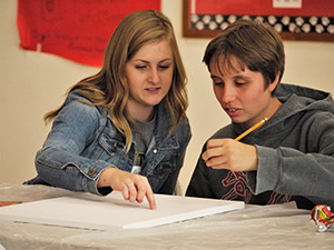 A student volunteer and a participant talk about how to get started on a drawing.
