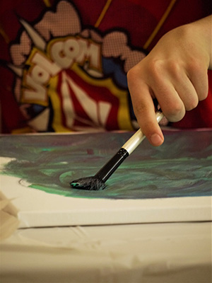 A close-up of a participant paining on a canvas.
