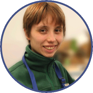 Johanna is smiling and looking directly at the camera. She is wearing an apron over a green fleece jacket.