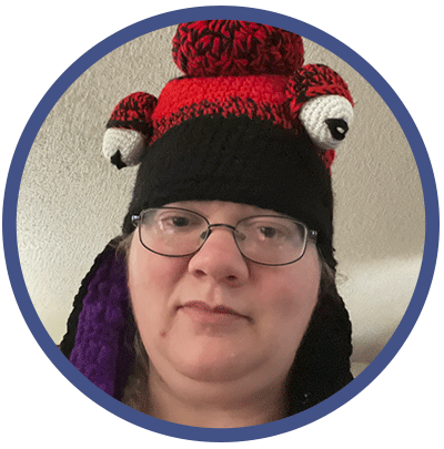 Jessilyn is looking down at the camera with a blank expression on her face. She is wearing glasses and a silly winter hat.