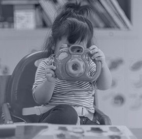 A little girl plays with a toy camera.