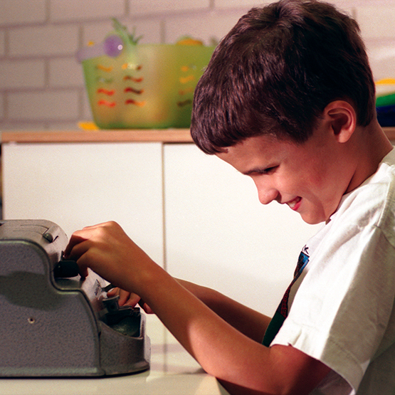 School age boy at a Braille typewriter.